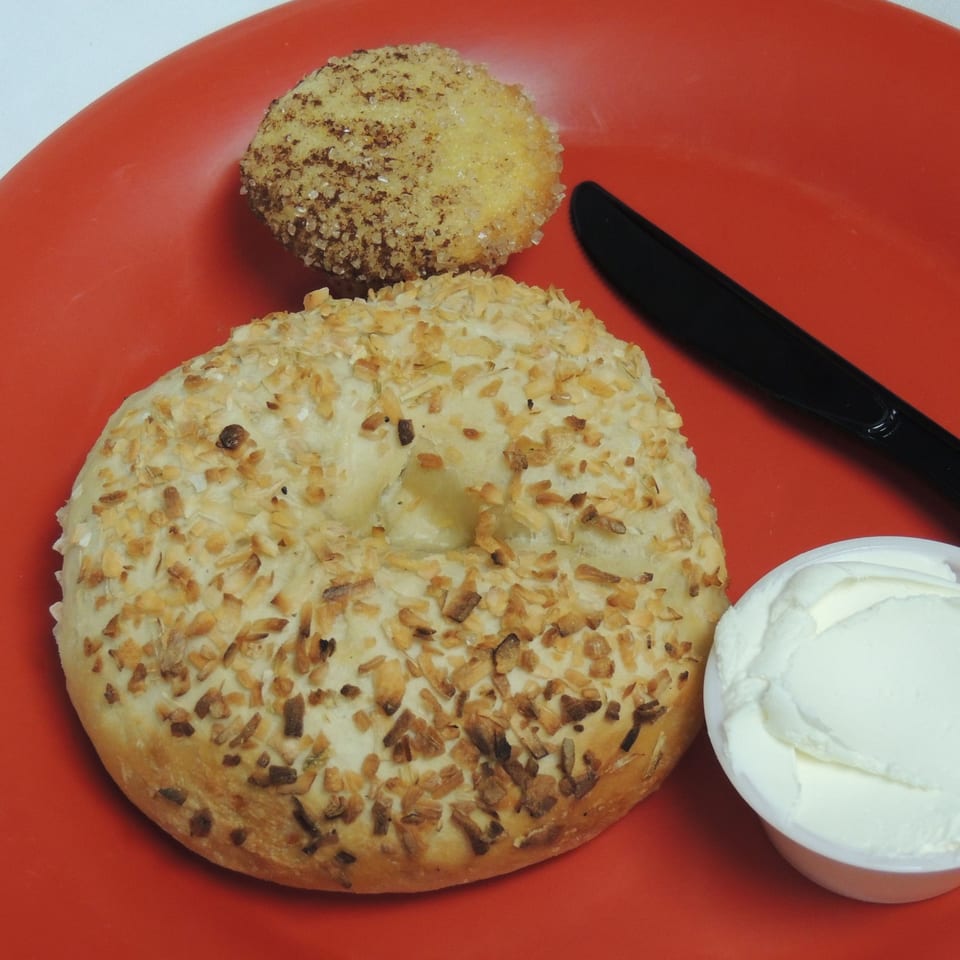 Ruby K's Bagel Cafe's onion bagel, bagel bite, and cream cheese on a red plate with a knife.