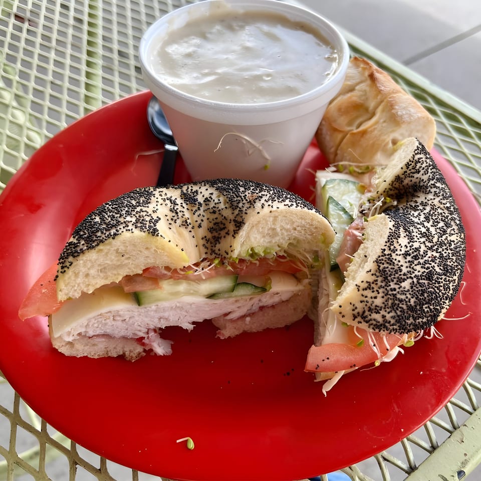 Ruby K's poppy seed bagel sandwich with turkey, cheese, tomato, cucumber, and sprouts, with soup.